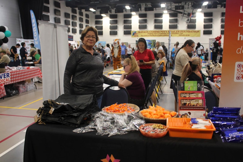 Volunteer at community health fair booth with snacks and giveaways